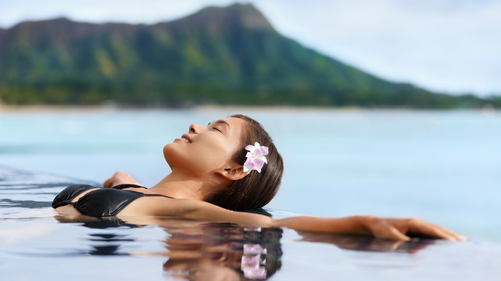 girl relaxing in a pool with Diamond Head in the background